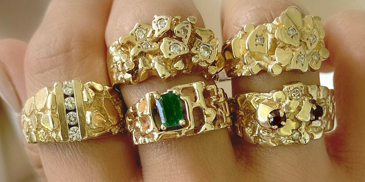 A selection of gold nugget vintage and antique rings with diamonds rubies and emeralds shown on hand