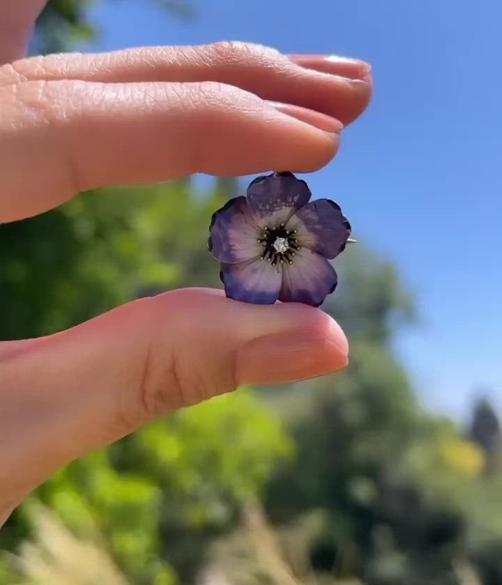 Video of an antique edwardian art nouveau purple, pink, white, and black enamel dogwood flower brooch and pendant with an Old Mine Cut diamond, shown in hand