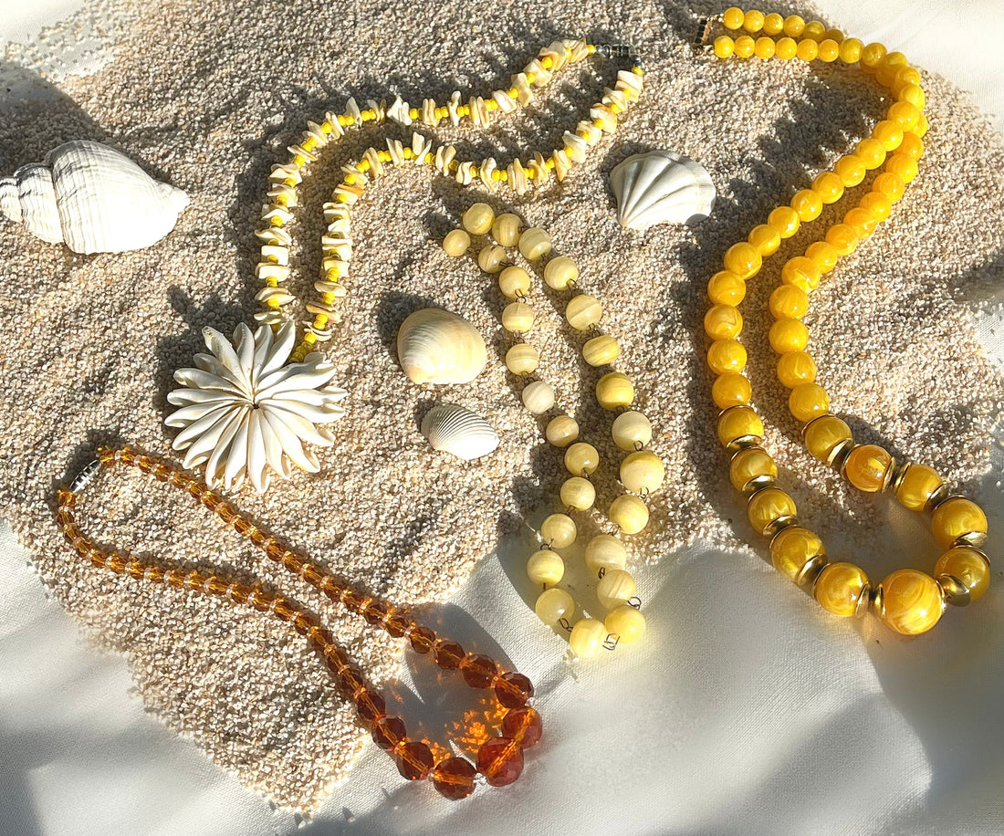A collection of various vintage costume jewelry necklaces on sand
