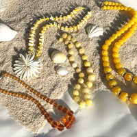 A collection of various vintage costume jewelry necklaces on sand