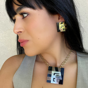 A vintage 1980s jewelry set of an Egyptian pharaoh profile in sterling silver, black, and gold, shown worn on a necklace and earrings, person in profile