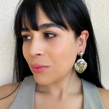 A woman with dark hair wearing a pair of vintage sterling silver earrings with a textured teardrop dangle drop