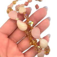 A close-up of a vintage 1950s Mid Century plastic and crystal pink and white and orange beaded necklace
