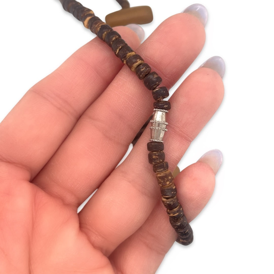A close-up of a silver tone clasp on a vintage 1970s wooden beaded necklace