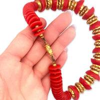 A close-up of a vintage 1980s red and gold beaded nautical style necklace