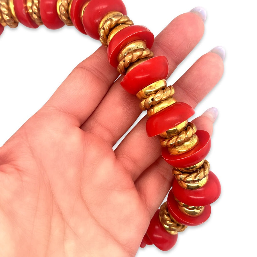 A close-up of a vintage 1980s red and gold beaded nautical style necklace