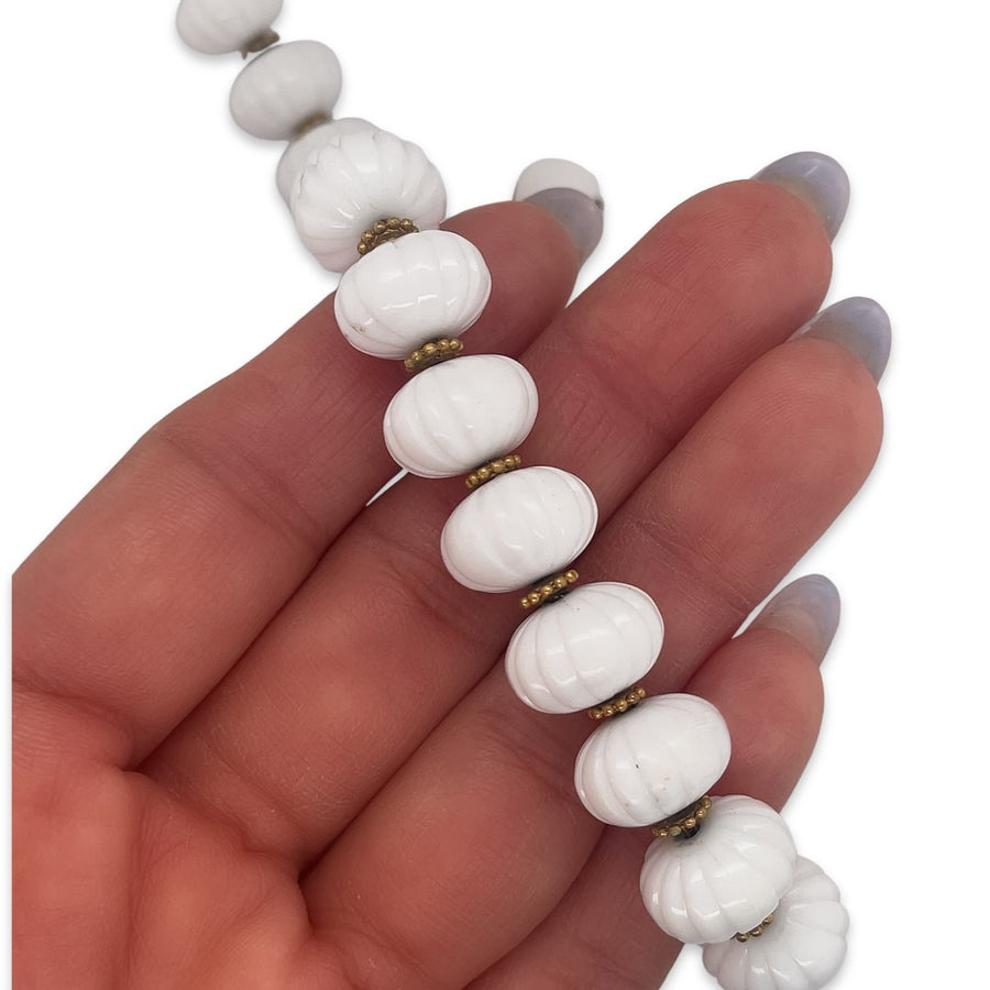 A vintage 1950s Mid Century era white ceramic beaded choker necklace with metal stations shown in hand for scale