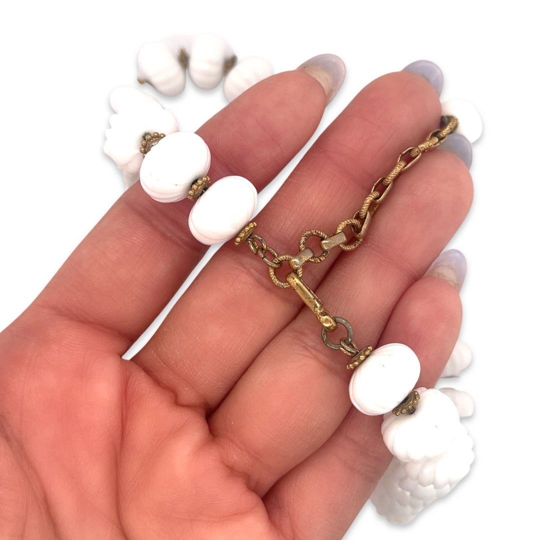 The metal clasp of a vintage Mid Century 1950s era white ceramic beaded costume jewelry necklace shown in hand for scale