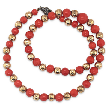 A vintage 1950s Mid Century era costume jewelry necklace with red coral beads and gold metal stations