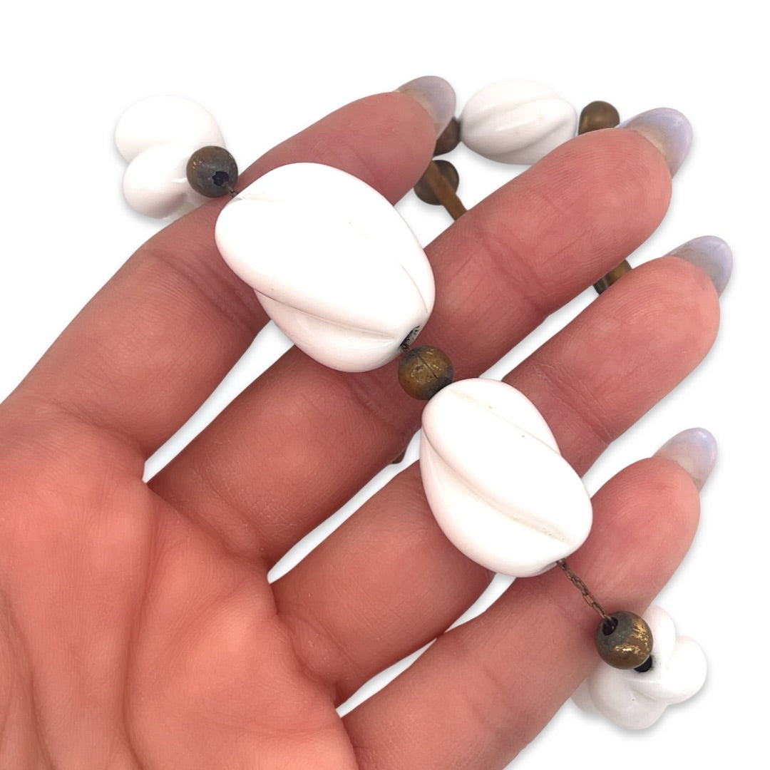 A close-up of a vintage 1950s Mid Century white ceramic bead and metal station necklace