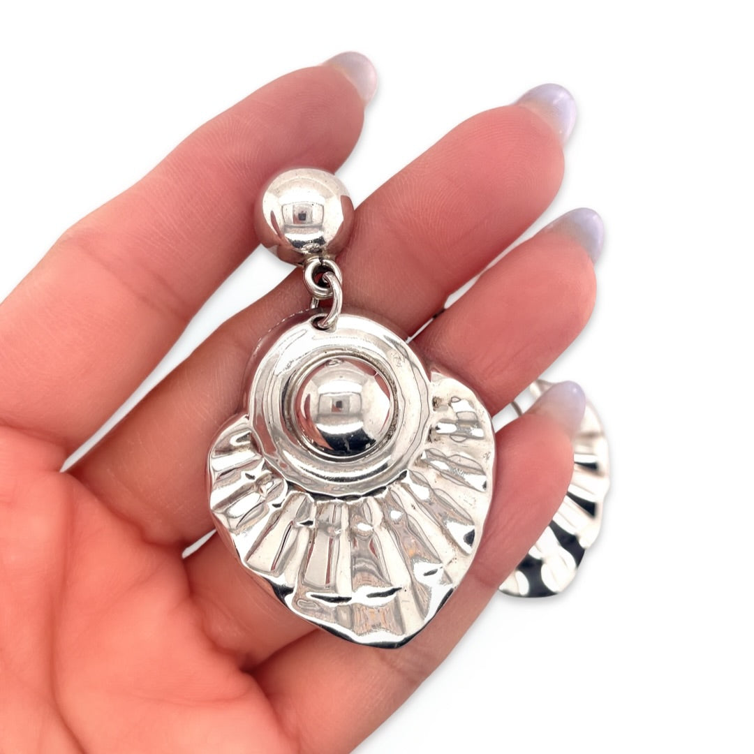 A close-up of a vintage sterling silver earring with a textured dangle drop