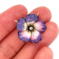 An antique edwardian art nouveau purple, pink, white, and black enamel dogwood flower brooch and pendant with an Old Mine Cut diamond, shown in hand