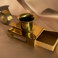 A vintage brass candlestick holder with handle and matchbox and striker