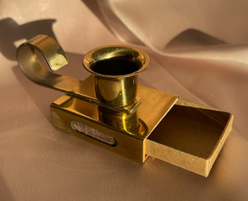 A vintage brass candlestick holder with handle and matchbox and striker