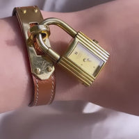 A vintage Hermès Paris circa 2000's mid aughts Kelly style lock wristwatch with a brown leather strap and gold-plated hardware