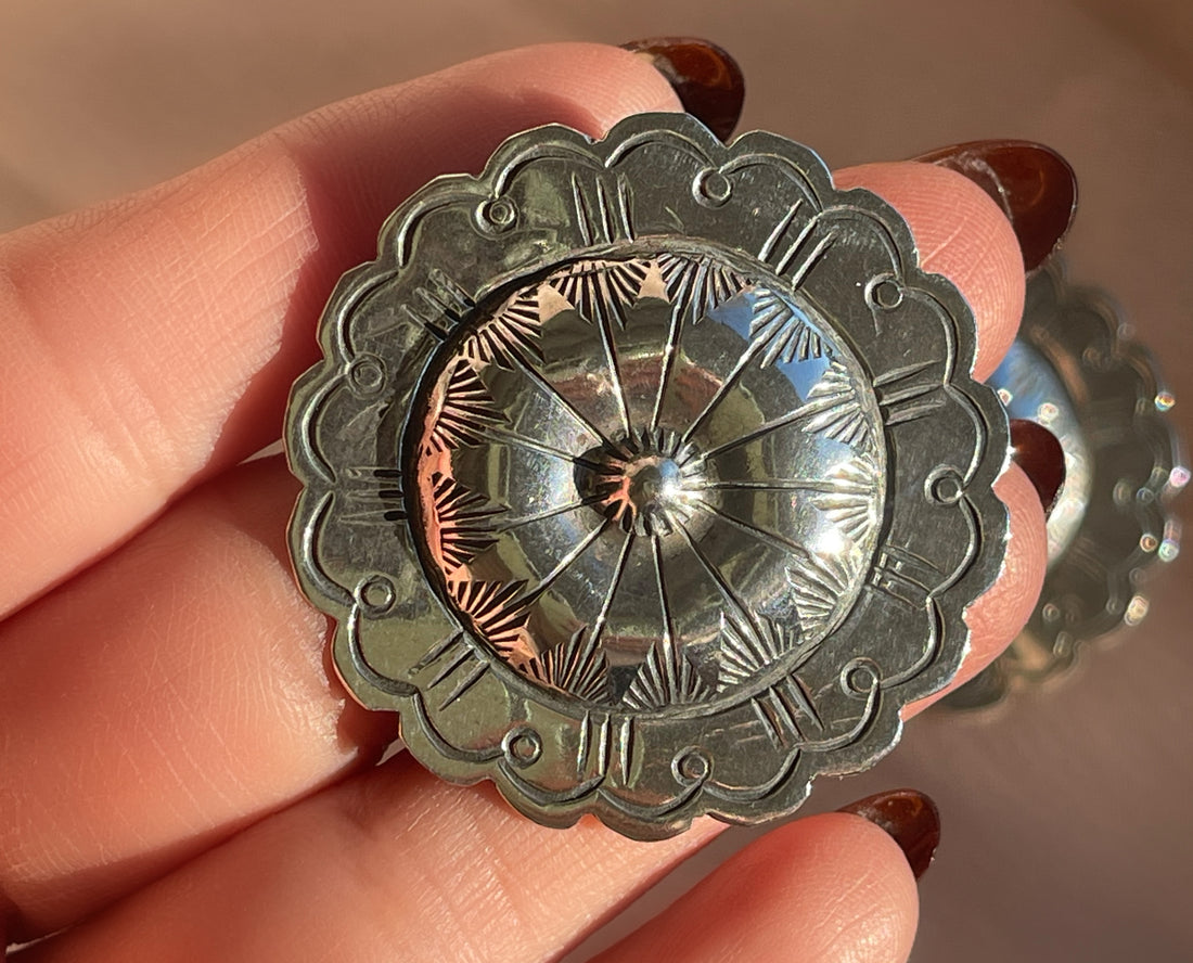 A pair of hand hammered stamped Native American Navajo concho shaped stud statement earrings in sterling silver