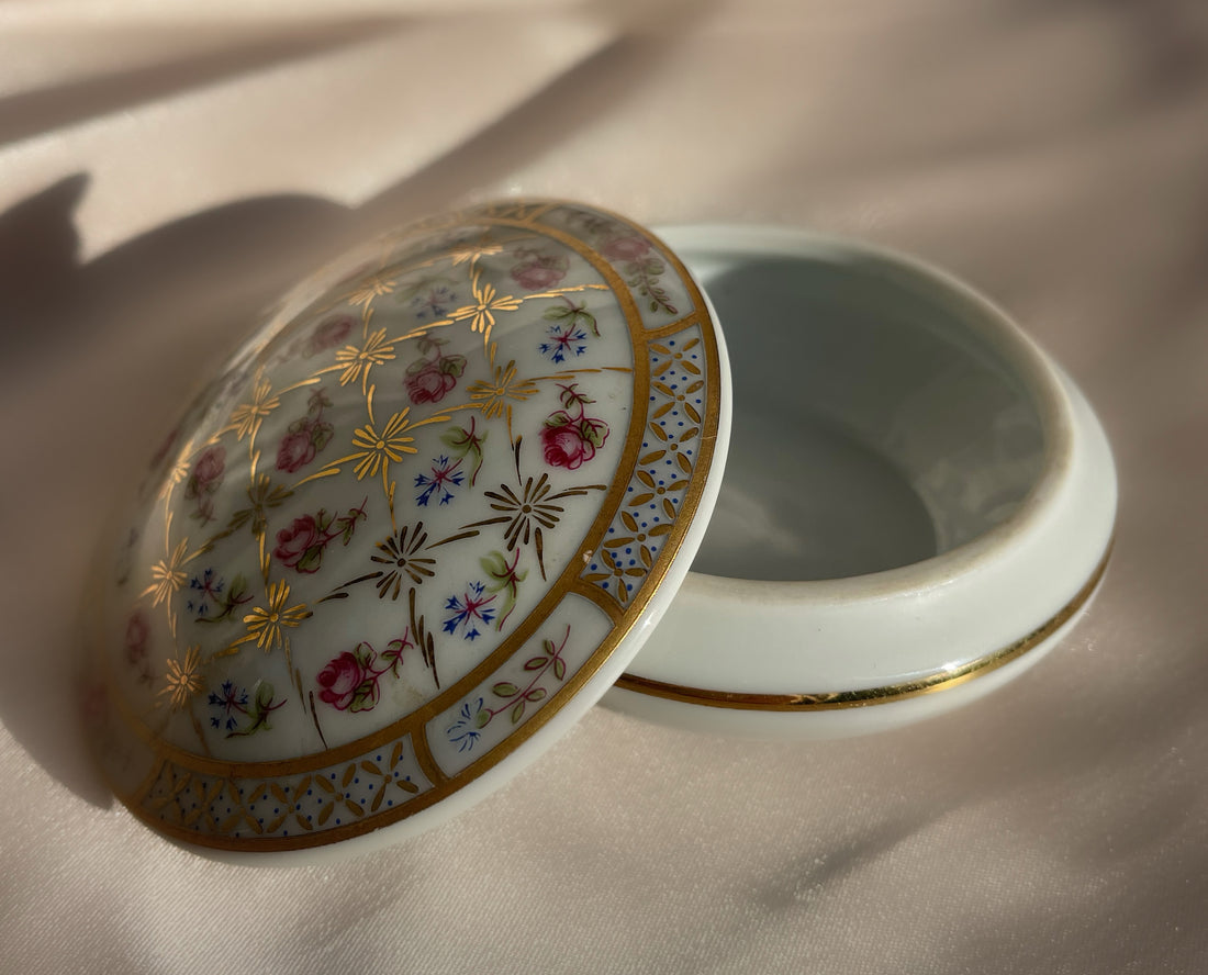 A vintage lidded porcelain jewelry trinket box with floral design and gold trim