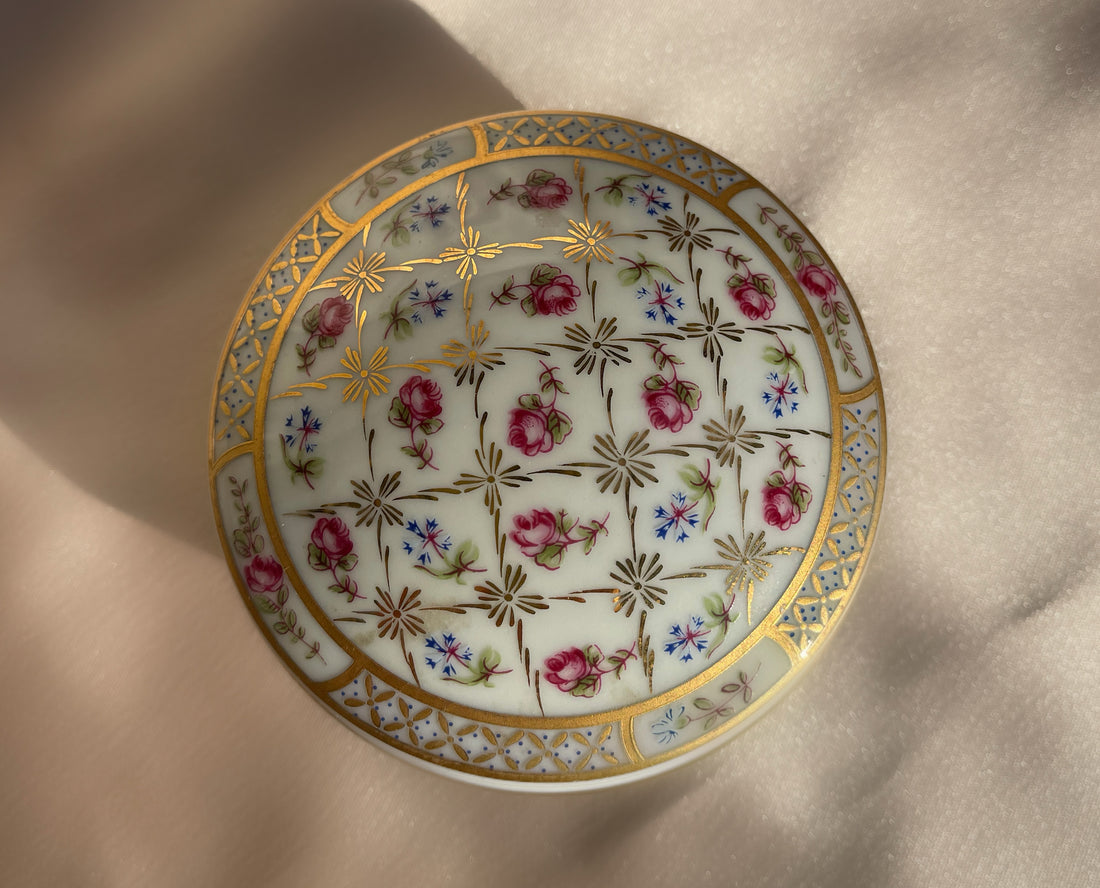 A vintage lidded porcelain jewelry trinket box with floral design and gold trim