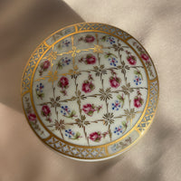 A vintage lidded porcelain jewelry trinket box with floral design and gold trim