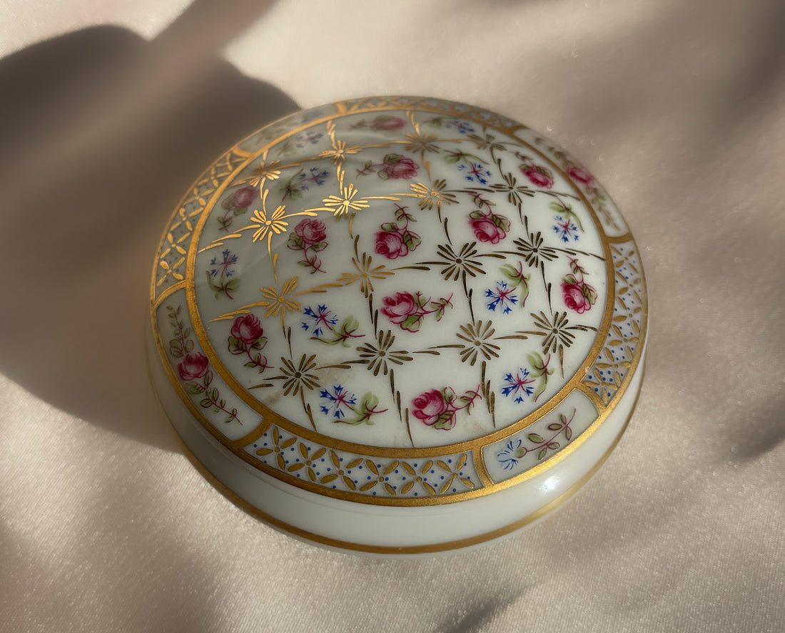 A vintage lidded porcelain jewelry trinket box with floral design and gold trim