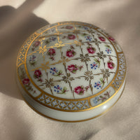 A vintage lidded porcelain jewelry trinket box with floral design and gold trim