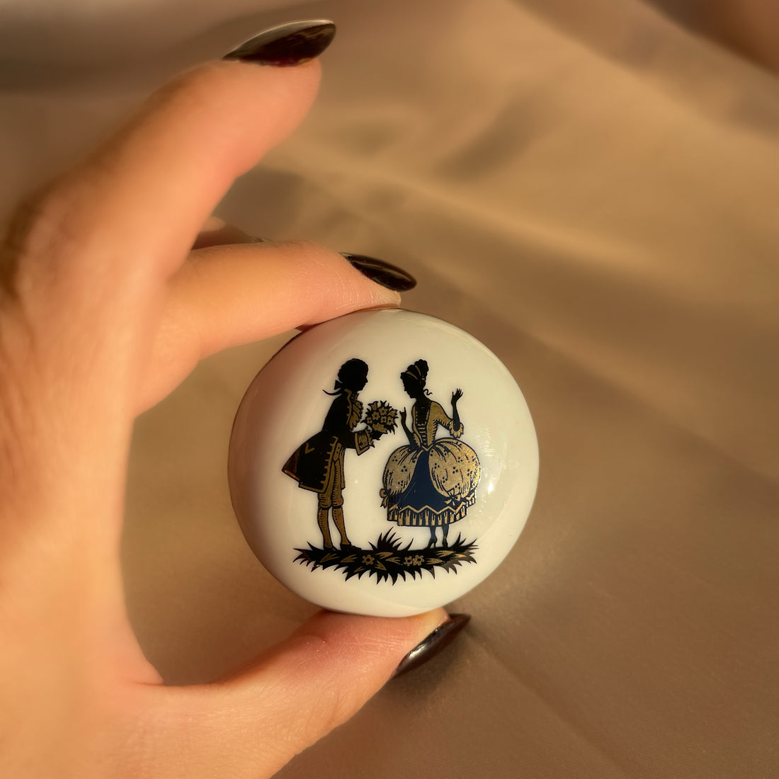 Vintage white porcelain jar with two black and gold embossed lovers