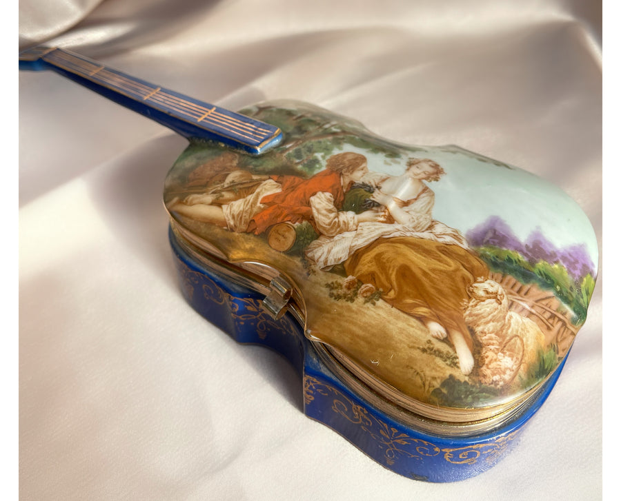 A 1980s eighties violin shaped lidded jewelry trinket box with a painting of a couple on the lid