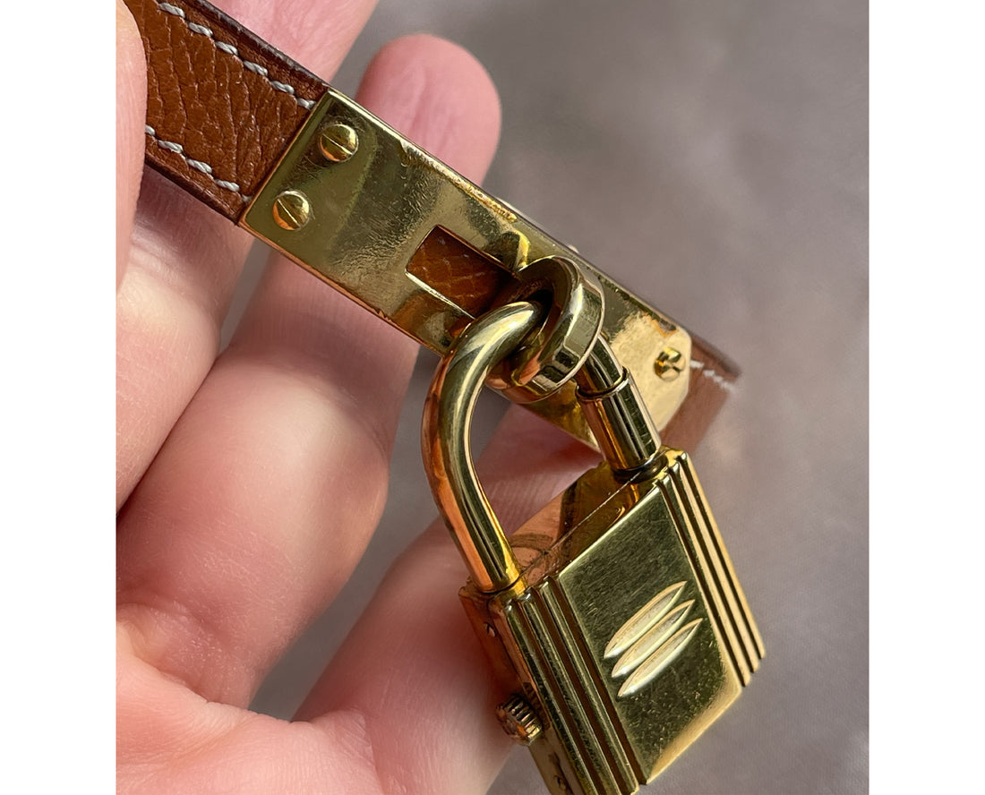 A vintage Hermès Paris circa 2000's mid aughts Kelly style lock wristwatch with a brown leather strap and gold-plated hardware