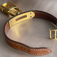 A vintage Hermès Paris circa 2000's mid aughts Kelly style lock wristwatch with a brown leather strap and gold-plated hardware