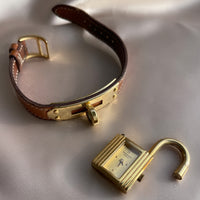 A vintage Hermès Paris circa 2000's mid aughts Kelly style lock wristwatch with a brown leather strap and gold-plated hardware