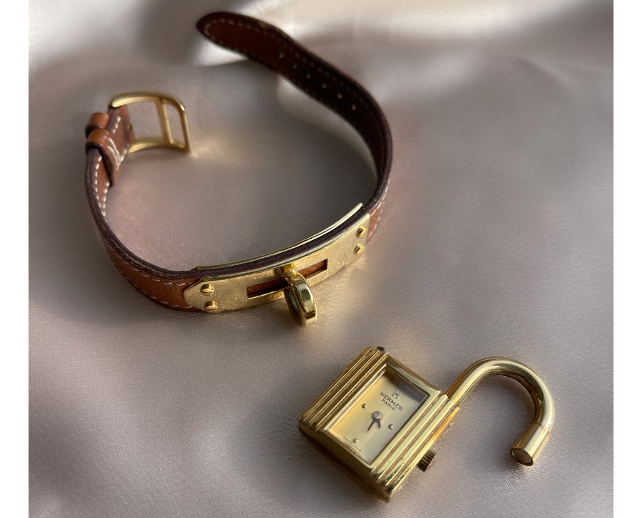 A vintage Hermès Paris circa 2000's mid aughts Kelly style lock wristwatch with a brown leather strap and gold-plated hardware