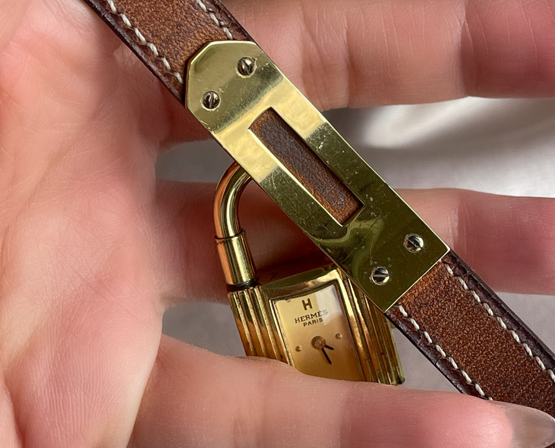 A vintage Hermès Paris circa 2000's mid aughts Kelly style lock wristwatch with a brown leather strap and gold-plated hardware