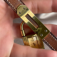 A vintage Hermès Paris circa 2000's mid aughts Kelly style lock wristwatch with a brown leather strap and gold-plated hardware