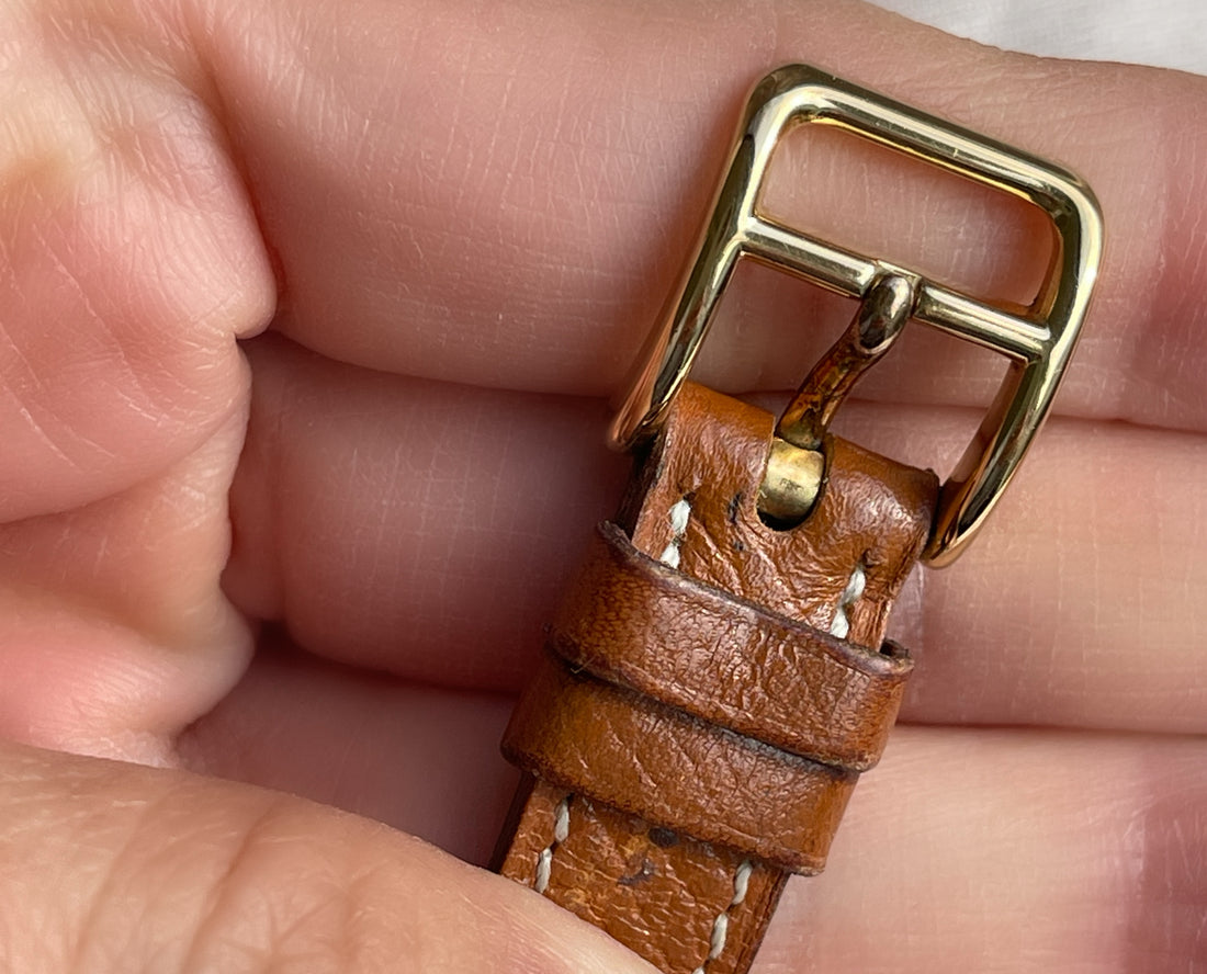 A vintage Hermès Paris circa 2000's mid aughts Kelly style lock wristwatch with a brown leather strap and gold-plated hardware