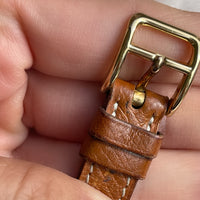 A vintage Hermès Paris circa 2000's mid aughts Kelly style lock wristwatch with a brown leather strap and gold-plated hardware