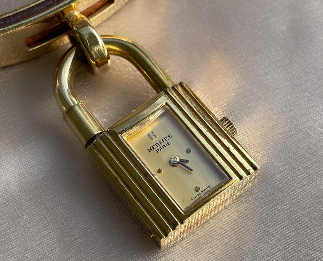 A vintage Hermès Paris circa 2000's mid aughts Kelly style lock wristwatch with a brown leather strap and gold-plated hardware