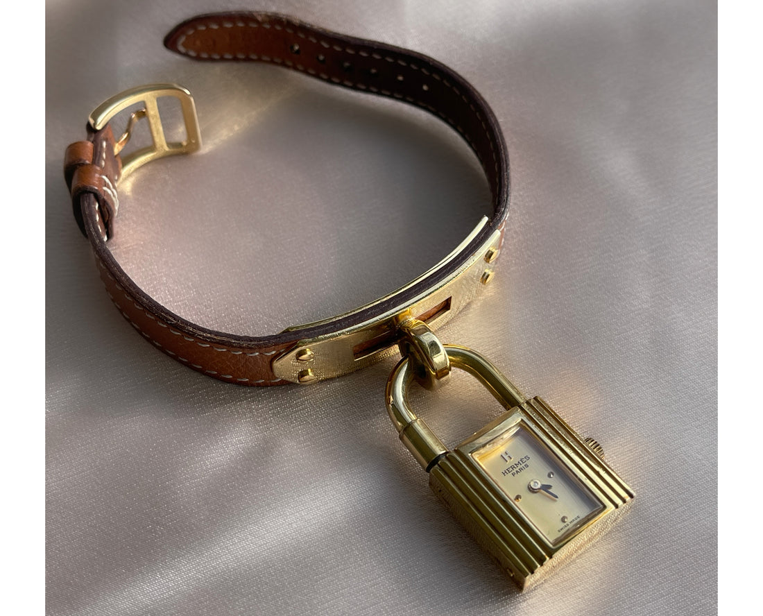 A vintage Hermès Paris circa 2000's mid aughts Kelly style lock wristwatch with a brown leather strap and gold-plated hardware