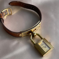 A vintage Hermès Paris circa 2000's mid aughts Kelly style lock wristwatch with a brown leather strap and gold-plated hardware